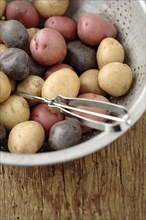 Peeler in colander with multicolored potatoes
