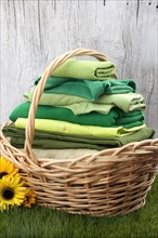 Basket of folded green clothes in grass