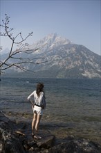 Caucasian woman standing in Jenny Lake admiring Great Teton mountains