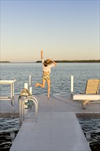 Caucasian woman jumping for joy on pier