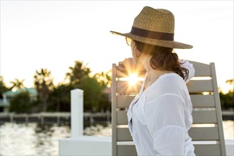 Caucasian woman admiring sunset from deck chair