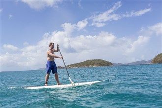 Caucasian man standing on paddle board on ocean