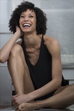 Laughing Mixed Race woman sitting on counter