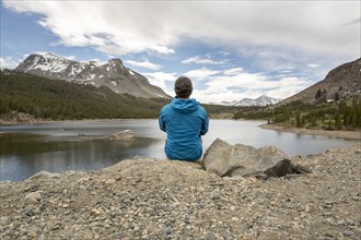 Caucasian man sitting on rock near lake