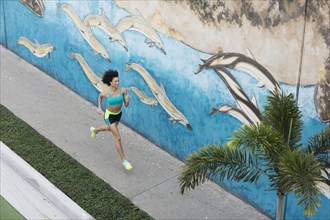 High angle view of Mixed Race woman running on sidewalk near mural
