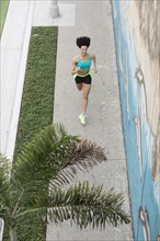 High angle view of Mixed Race woman running on sidewalk near mural