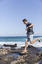 Caucasian man running on rocks on beach