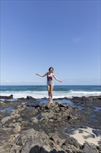 Mixed Race woman standing on rocks on beach