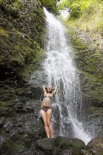 Caucasian woman standing on rock near waterfall