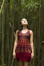 Caucasian woman standing in bamboo forest and looking up