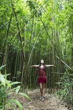 Caucasian woman standing in bamboo forest and looking up