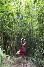Caucasian woman standing in bamboo forest performing yoga