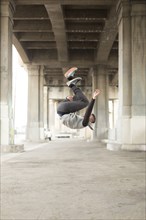 Mixed Race man jumping upside-down under bridge