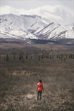 Caucasian woman standing in field near snowy mountain
