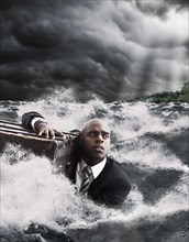 African American businessman in ocean holding trunk