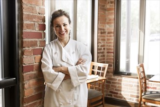 Hispanic chef leaning against wall in cafe