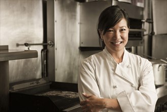 Smiling Chinese chef standing in commercial kitchen