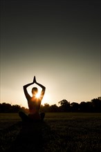Caucasian woman practicing yoga at sunset