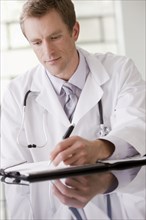 Caucasian doctor writing in medical record