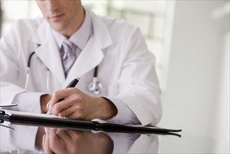 Caucasian doctor writing in medical record
