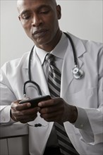 African American doctor text messaging on cell phone