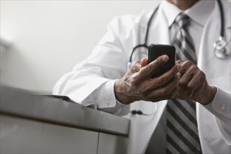 African American doctor text messaging on cell phone