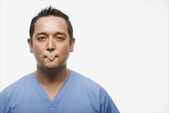 Mixed race doctor with bandages over his mouth