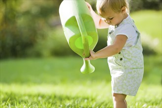 Caucasian baby lifting watering can