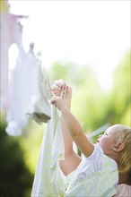Caucasian mother and baby hanging laundry on clothes line