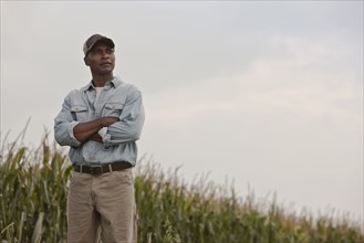 African American man standing in field with arms crossed