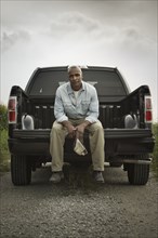 African American sitting on back of pick-up truck