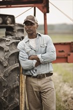 African American farmer standing near tractor