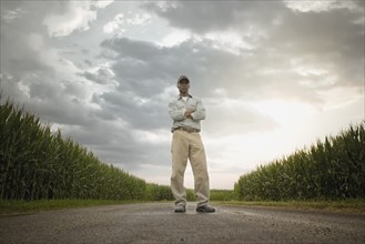 African American farmer standing on road through crops