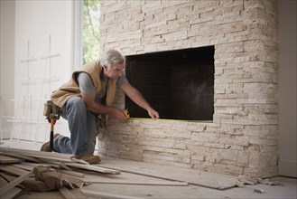 Caucasian carpenter measuring fireplace