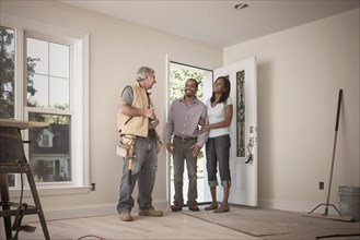 Carpenter talking to couple in empty room