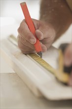 Caucasian carpenter measuring lumber