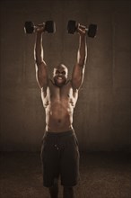 Grimacing African American man lifting weights