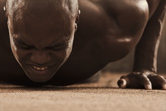Grimacing African American man doing push-ups