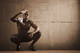 African American man pouring water over himself after exercise