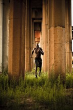 African American man jogging between pillars