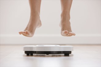 Caucasian woman's feet jumping on scale