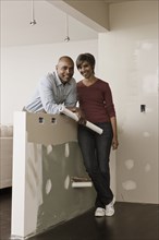 Couple standing in unfinished room with blueprints