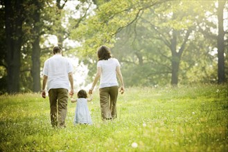 Parents walking with daughter in field