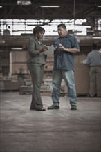 Businesswoman talking to worker in warehouse