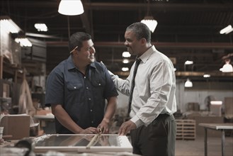 Businessman talking to worker in warehouse