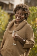 Black woman drinking wine in vineyard