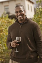 Black man drinking wine in vineyard