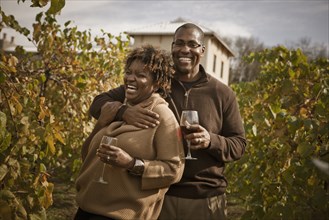 Black couple drinking wine in vineyard