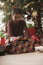Hispanic boy opening gifts Christmas morning