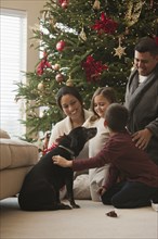 Family petting dog in living room on Christmas morning